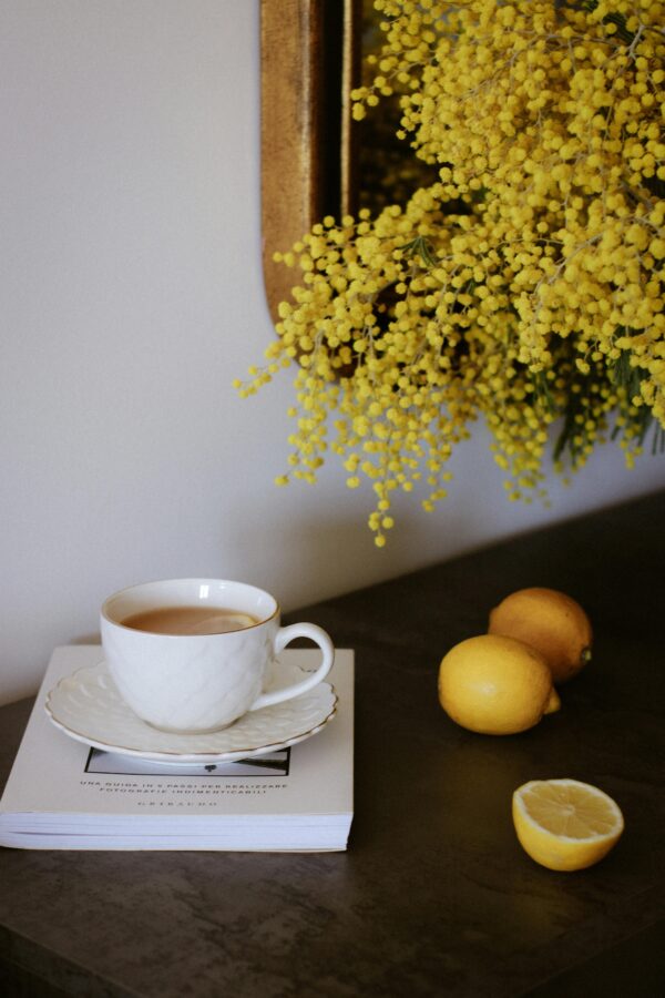 Elegant tea setting with lemons and mimosa flowers on a table for a warm and inviting atmosphere.