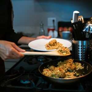 Close-up of a person serving delicious home-cooked fried rice from a pan in a kitchen setting.