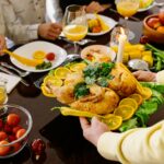A delicious roasted chicken with lemon slices being served at a festive family dinner table.