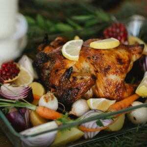 Delicious roast chicken surrounded by fresh vegetables, perfect for a holiday feast.